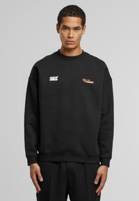 Sudadera negra de algodón con un corte relajado. Presenta texto bordado en blanco y naranja en el pecho. Puños y dobladillo acanalados.