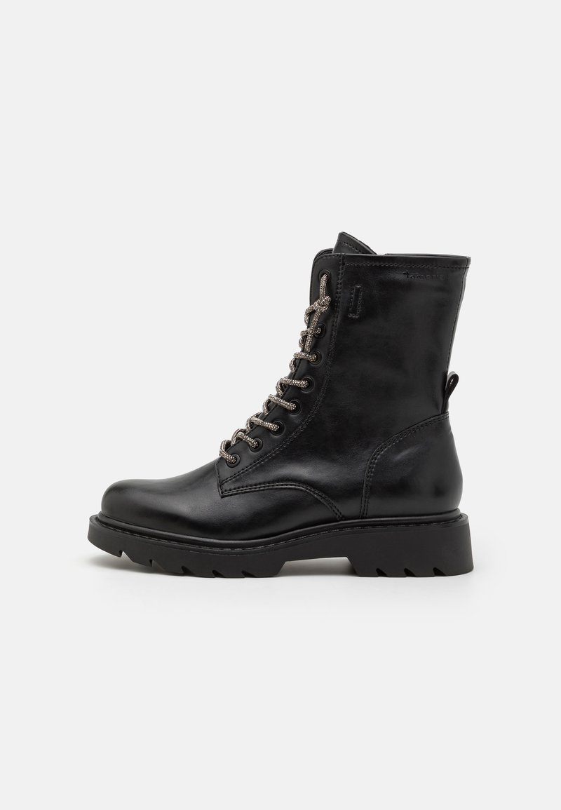 Bottine noire en cuir avec un bout rond, surface texturée, accents de lacets métalliques et une semelle robuste. Dispose d'une sangle à l'arrière.