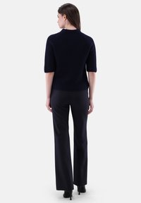 Navy-blauer, gerippter Strickpullover mit kurzen Ärmeln, taillierter Form und texturiertem Stoff, kombiniert mit schwarzen, maßgeschneiderten Hosen.