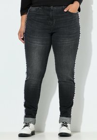 Jeans de denim gris oscuro con corte ajustado, que presentan una franja lateral con un diseño y dobladillos enrollados. El material es ligeramente texturizado y cuenta con bolsillos clásicos.