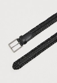 El cinturón de cuero trenzado negro cuenta con un lazo de cuero liso y una hebilla de metal de tono plateado, enfatizando la textura y la artesanía.