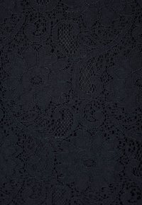 Černá krajka s jemnými květinovými a paisley vzory a texturovaným povrchem. Průsvitné části vytvářejí vrstvený vzhled.