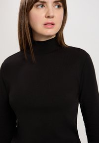 Czarny top z golfem wykonany z prążkowanej tkaniny, charakteryzujący się wysokim kołnierzem i długimi rękawami, o dopasowanym kroju.