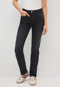 Zwarte spijkerbroeken met een slim fit, vijf zakken en een knoopsluiting. Draagt met witte en bordeauxrode sneakers. Zachte textuur, klassiek ontwerp.