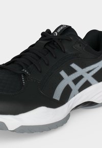 Αθλητικό παπούτσι Asics ασπρόμαυρο με μαύρα κορδόνια, πλέγμα στη μύτη και γκρι μοτίβο λογότυπου Asics στο πλάι, σε λευκό φόντο.