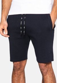 Marineblå bomuldsshorts med elastisk talje og snore, sidelommer og et struktureret stofmønster. Logo detaljer på benet.