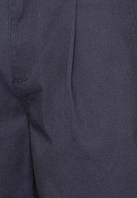 Närbild av marinblått tyg med synliga sömmar och stygn, som visar struktur och lätta rynkor.