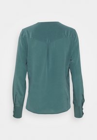 Langarmshirt aus teal Satin, mit rundem Ausschnitt, mittigem Rückenfalten und Knopfmanschetten. Glatte Textur mit subtiler Satinoptik.