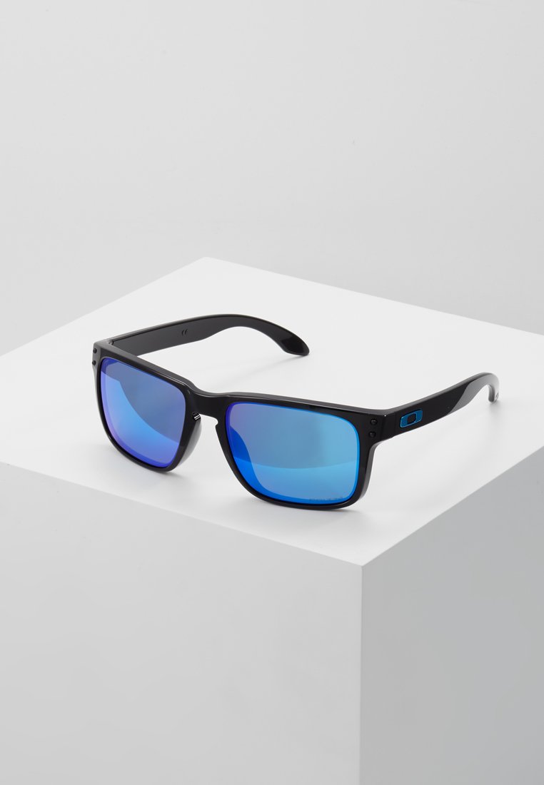 Ochelari de soare rectangulari negri cu lentile pictate în nuanțe de albastru. Au un finisaj mat și detalii cu logo pe tâmplă. Design robust al ramei.