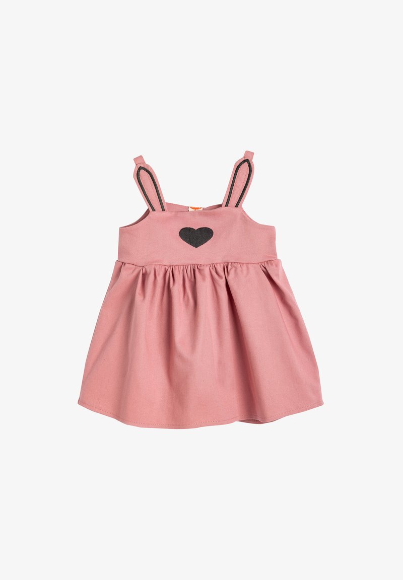 Rosa Baumwollkleid mit verstellbaren Trägern, gerafftem Rock und einer schwarzen Herzenapplikation auf der Brust. Mit Hasenohren-Akzenten an den Trägern.