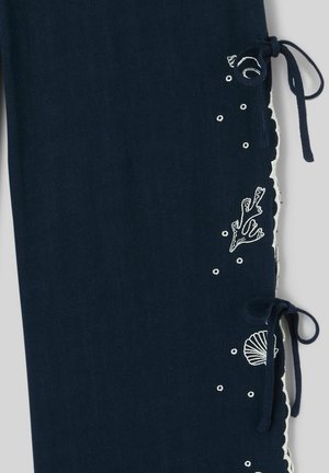 Tissu bleu marine avec des motifs marins blancs brodés et deux nœuds noués le long du bord festonné.