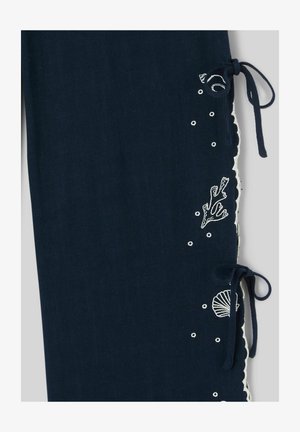 Tissu bleu marine avec des motifs marins blancs brodés et deux nœuds noués le long du bord festonné.