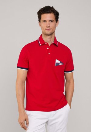 Rode polo-shirt met een kraag en blauw-witte strepen. Geborduurd driehoekig zakdetail voegt contrast toe. Korte mouwen.