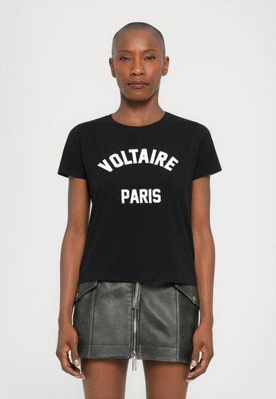 Tricou negru din bumbac cu imprimeu alb "VOLTAIRE PARIS". Dispune de un guler rotund și mâneci scurte, fiind asortat cu o fustă din piele gri.