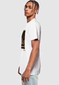 White cotton t-shirt featuring a graphic print of a city scene on the front. Short sleeves, round neckline, standard fit.