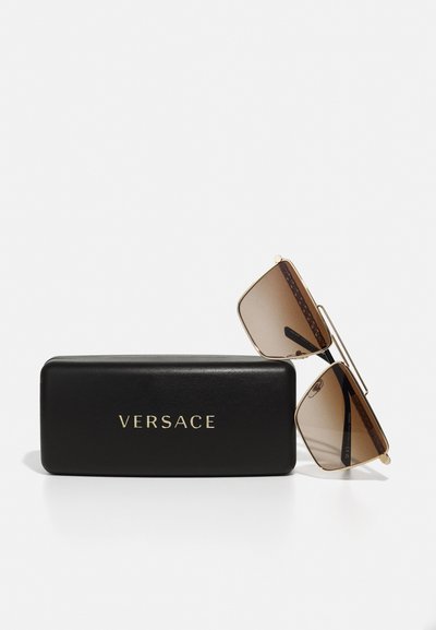 Ochelari de soare Versace cu lentile gradiente maro, ramă metalică aurie și capac rectangular negru cu logo embosat în aur.