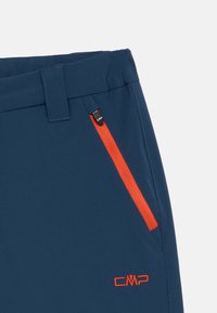 Σκούρο μπλε παντελόνι με πορτοκαλί τσέπη φερμουάρ, φτιαγμένο από λεία ύφανση. Διαθέτει ραμμένη ζώνη και ένα μικρό κόκκινο λογότυπο στο πλάι.