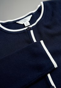 Cardigan bleumarin cu margini albe. Are textură striată, guler rotund și închidere cu nasturi. Eticheta spune „THE SET,” mărimea M.