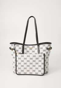 Torba typu tote w białym syntetycznym materiale z czarnym nadrukiem logo, skórzanymi akcentami na paskach i złotymi elementami wykończenia. Otwarta konstrukcja z przestronnym wnętrzem.