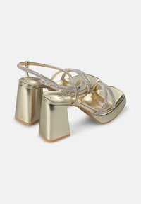 Gold block-heel sandals with rhinestone-embellished straps and a smooth metallic finish. Features a square toe design and rubber sole.