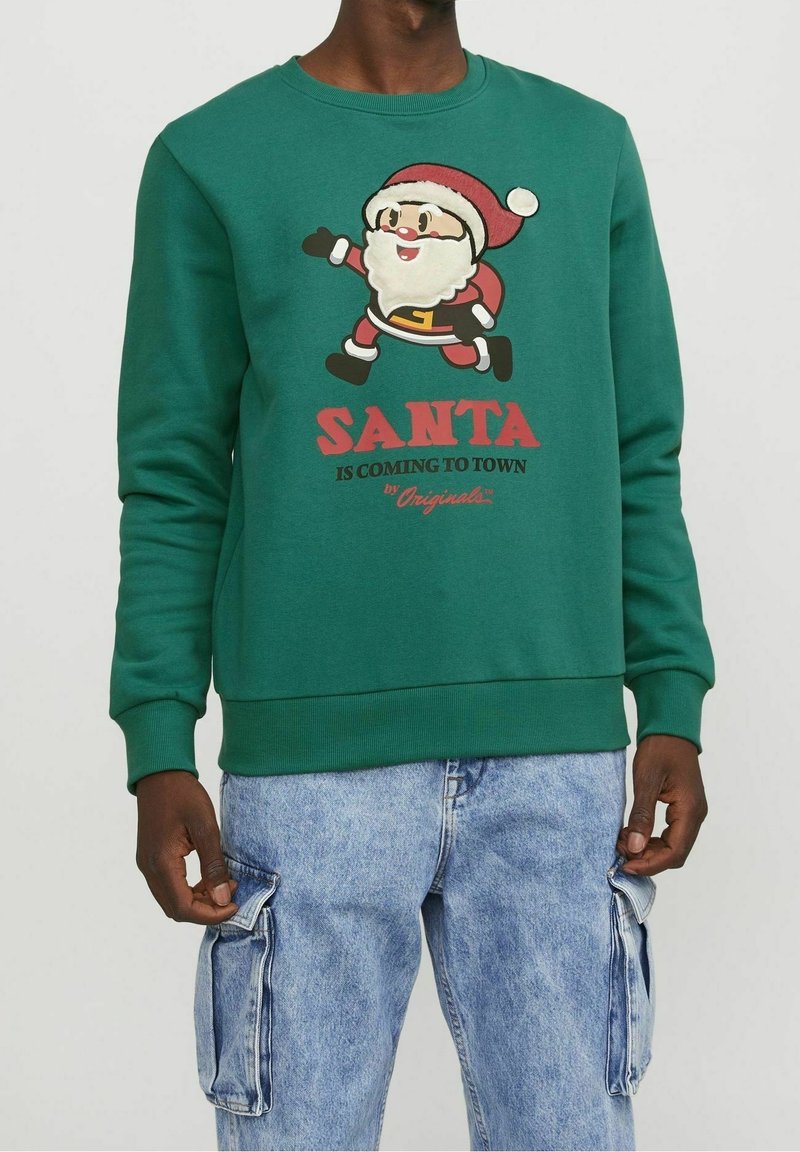 Groene sweatshirt met een cartoon Santa met een rode hoed, witte baard en rode tas, de tekst eronder luidt "SANTA KOMT NAAR DE STAD."