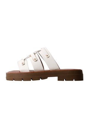 Sandale slide en cuir blanc avec trois brides et rivets dorés, semelle épaisse en caoutchouc marron avec un motif de semelle profond.