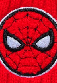 Tessuto rosso lavorato a maglia con un design prominente di una maschera circolare di Spiderman. Presenta contorni neri, occhi bianchi e un motivo a ragnatela testurizzato.