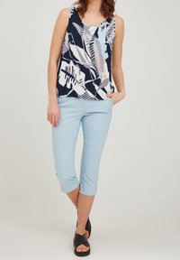 Top sin mangas a rayas en navy, blanco y azul claro, combinado con pantalones cortos azul claro y sandalias negras con tiras cruzadas.