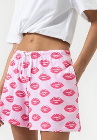 Roze shorts met een herhalend lippenpatroon, elastische tailleband, zijzakken en een trekkoord, gemaakt van zachte stof.
