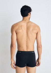 Zwarte katoenen boxershorts met een Calvin Klein-logo op de tailleband, eenvoudig ontwerp, met een aansluitende pasvorm en tot halverwege de dijen.