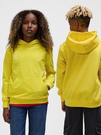 Deux jeunes, l’un tourné vers l’avant et l’autre vers l’arrière, tous deux portant des sweats à capuche jaune vif.