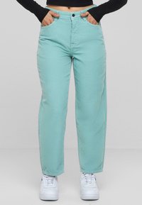 Pantaloni in velluto a coste di un verde menta chiaro con design a gamba dritta, dotati di tasche laterali e chiusura con bottone in vita.