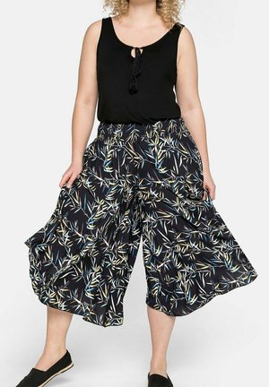 Top in cotone nero con dettaglio a chiave abbinato a pantaloni culotte ampi e fluidi in un tessuto nero con motivo di foglie di bamboo multicolore.