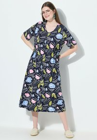 Niebieska sukienka z krótkim rękawem w kwiatowy wzór w odcieniach różu i niebieskiego, z okrągłym dekoltem i ściągniętą talią, co podkreśla sylwetkę.