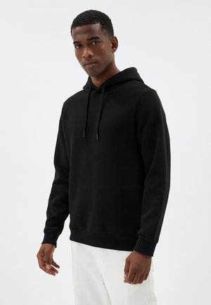 Zwarte hoodie met een trekkoordkap en ribgebreide manchetten, gemaakt van een zachte stof. Het ontwerp omvat een kangoeroezak en een comfortabele pasvorm.