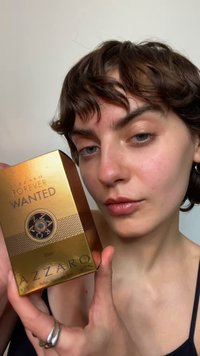 La boîte du parfum Azzaro Forever Wanted Elixir est dorée avec des accents texturés, ornée d'un emblème circulaire et de lettres noires. Taille : 50 ml.