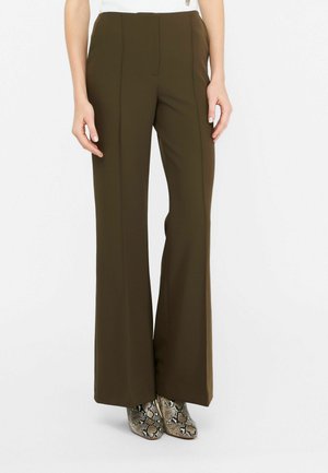 Pantaloni larghi marroni con una texture morbida, caratterizzati da pieghe davanti. Abbinati a stivali alla caviglia con stampa serpente a fantasia.
