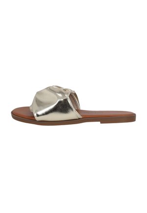 Sandale en métal doré avec un orteil arrondi, une large sangle incurvée et une semelle plate marron. Texture lisse avec un design minimaliste.