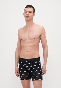 Fekete boxer alsónadrág ismétlődő fehér háromszög mintával, rugalmas derékháttal és illeszkedő kialakítással. Rugalmas, sima anyagból készült.