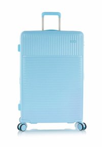 Lichtblauwe harde koffer met een telescopische handgreep en vier dubbele spinnerwielen die rechtop staan.