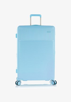 Valigia rigida azzurro chiaro con manico telescopico e quattro ruote doppie a scomparsa, in posizione verticale.
