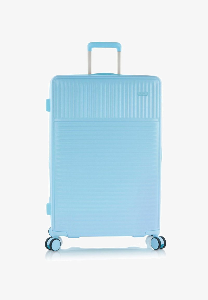 Maleta dura de color azul claro con un mango telescópico y cuatro ruedas dobles giratorias, en posición vertical.