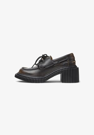 Chaussure en cuir noir à lacets avec semelle plateforme épaisse à rainures et talon bloc, avec des détails cousus et une étiquette de marque latérale.