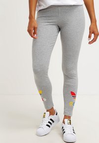 Grå leggings med färgglada Adidas-logotypaccents vid underbenen. Tillverkade av ett mjukt, flexibelt material med en åtsittande design. Bärs med vita sneakers.