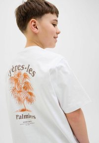 Valge puuvillane T-särk, millel on suur oranž palmipuu graafika ja seljal pruun tekst "Palmers". Lühikesed varrukad, mugav lõige.