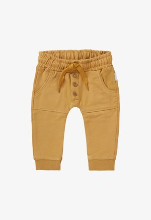 Pantalon de survêtement jaune avec taille élastique, cordon de serrage et fermeture à trois boutons. Dispose de poches latérales et de bords côtelés aux chevilles.