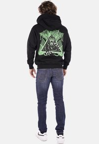 Felpa nera con grafica verde raffigurante un gorilla che ruggisce e un design geometrico sul retro. Materiale in pile, tasca a marsupio, polsini a costine.