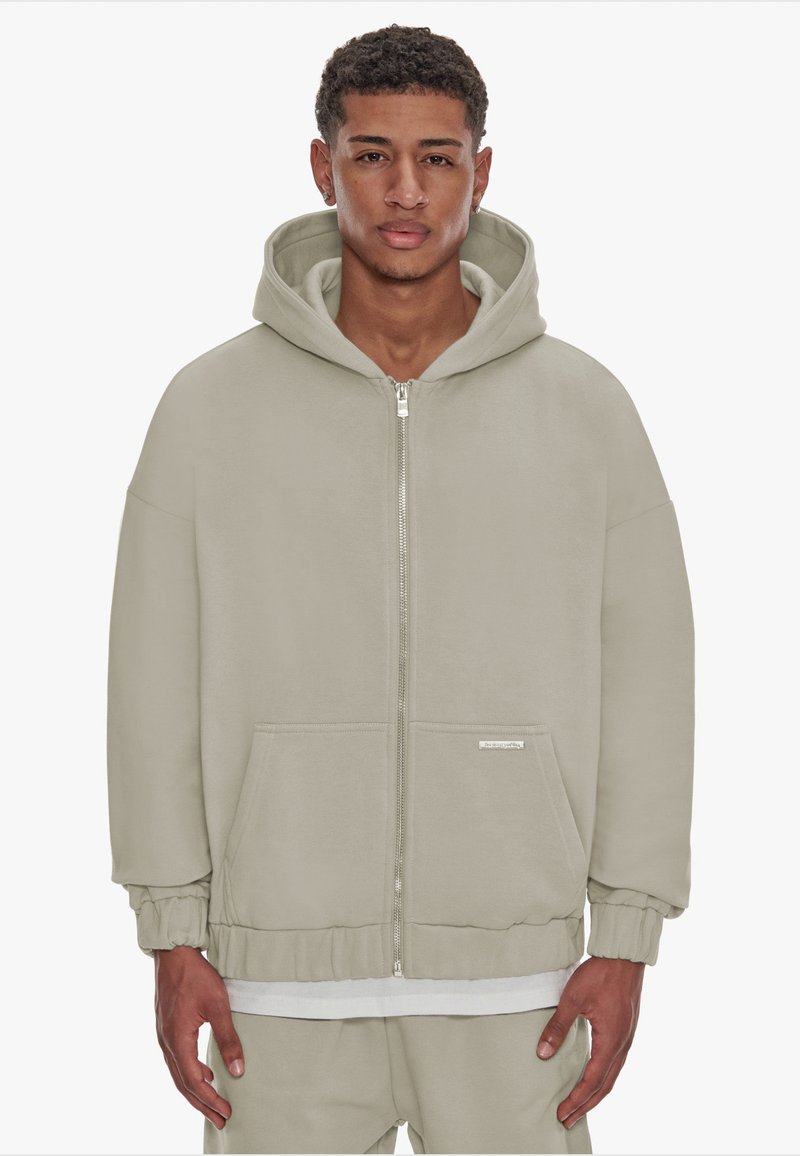 Light gray zip-up hoodie with a spacious hood, kangaroo pockets, elastic cuffs, and a drawstring hem. Made from soft fabric.