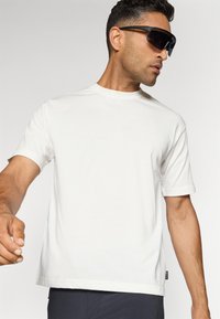 White short-sleeve t-shirt with a round neckline, made of smooth fabric. The design features rolled cuffs and a relaxed fit.