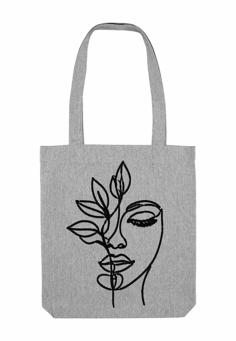 Grijze stoffen tas met een zwart geborduurd ontwerp van een gezicht dat verstrengeld is met bladeren, platte vorm en twee lange handvatten.
